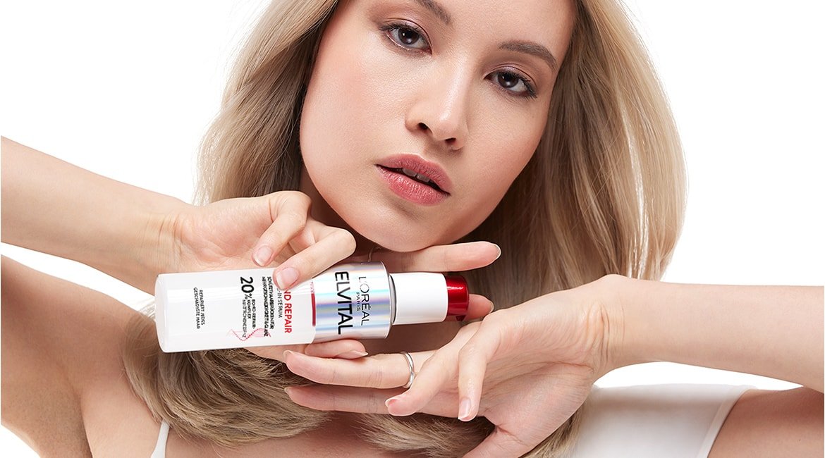 Eine Frau hält ein Elvital Bond Repair Produkt in ihrer Hand